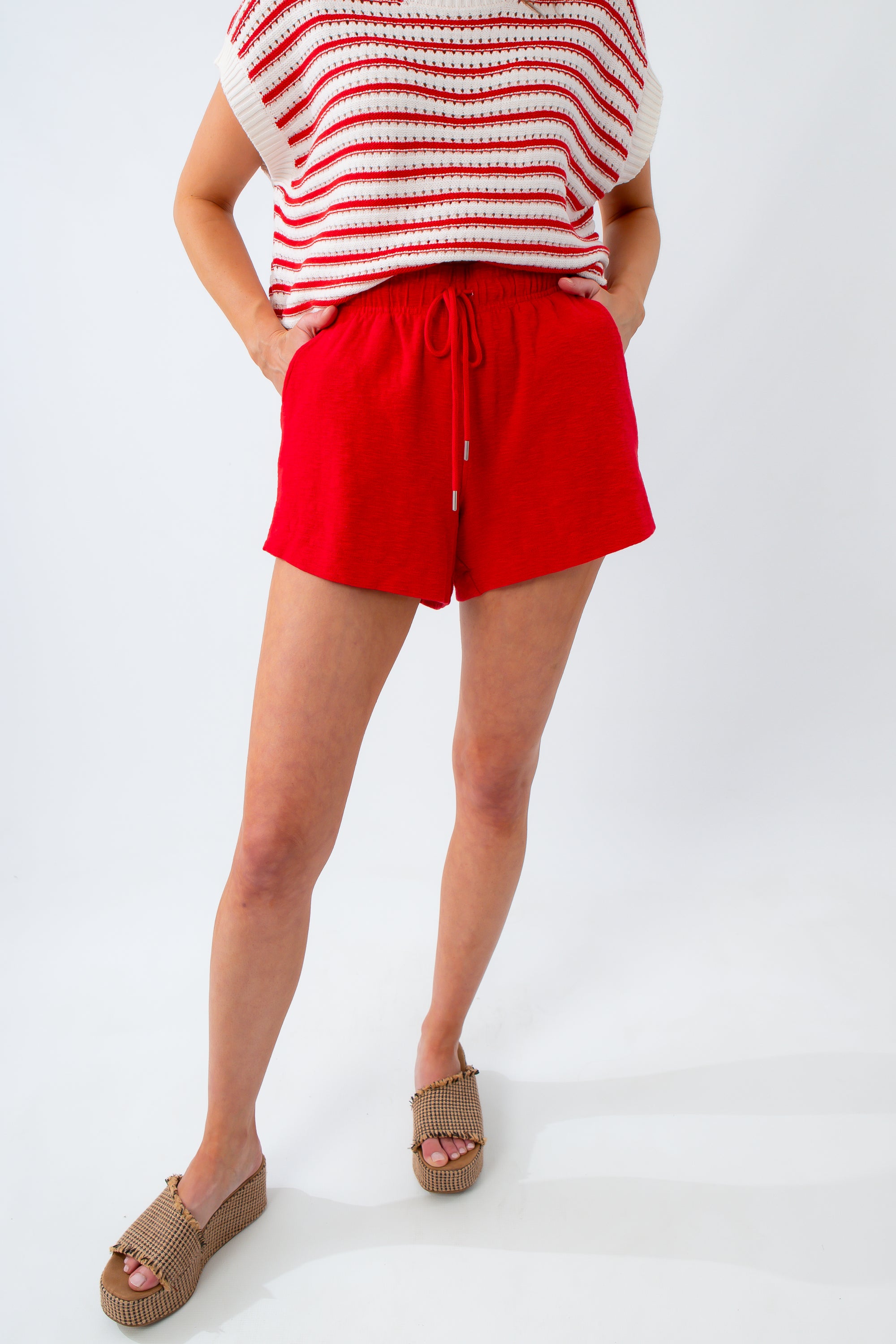 Person wearing red shorts and a striped top on a white background