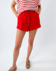 Person wearing red shorts and a striped top on a white background
