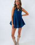 Woman wearing a blue denim set and cowboy boots with statement necklace on a white background