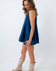 Woman wearing a blue dress and beige boots on a white background