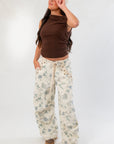 Model wearing Friday Feeling Brown Asymmetrical Top with floral pants and cap, showcasing a casual fall outfit.