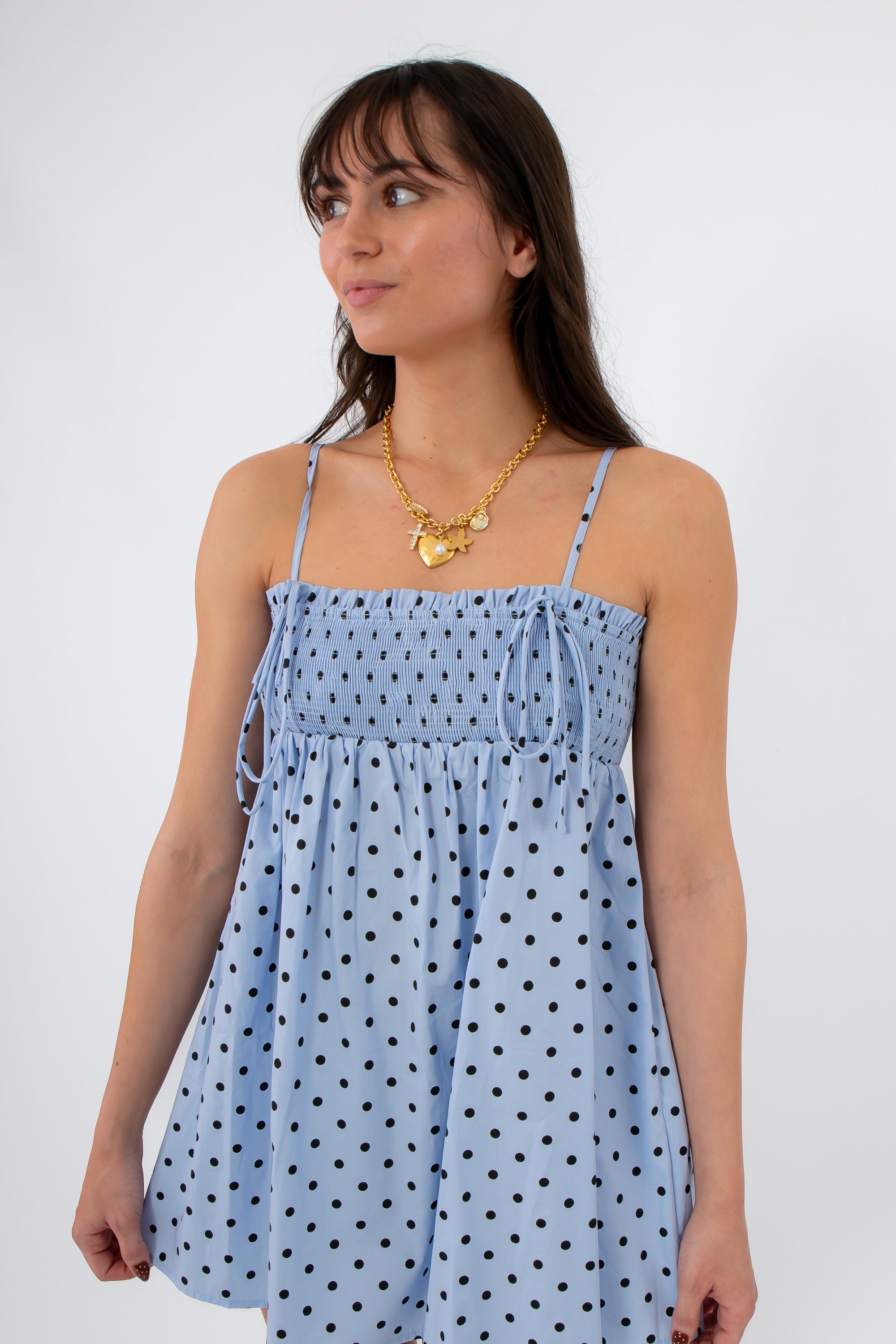 Close-up of light blue polka dot smocked mini dress with adjustable straps and gathered bodice