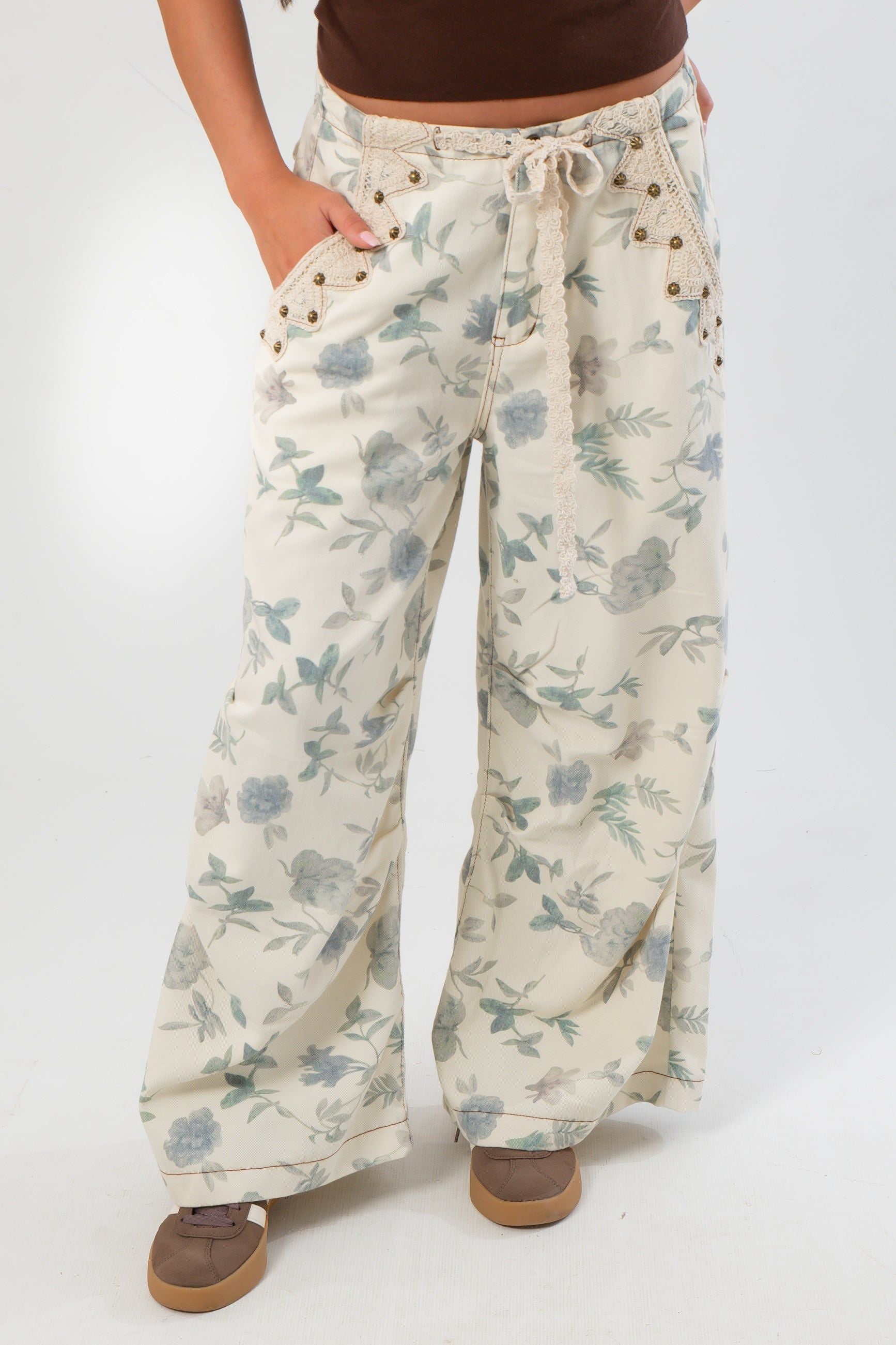 Close-up of Weston Cream Floral Barrel Jeans highlighting soft floral print, mid-rise waist, and grommet lace-up front design.