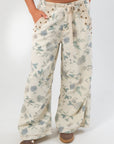 Close-up of Weston Cream Floral Barrel Jeans highlighting soft floral print, mid-rise waist, and grommet lace-up front design.