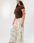 Side view of Friday Feeling Brown Asymmetrical Top styled with floral pants, highlighting the top’s flattering twist detail.
