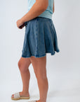 Person wearing a blue denim skirt on a white background