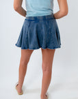 Person wearing a blue denim skirt and light blue top on a white background