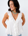 Woman wearing a white ruffled top and blue jeans against a white background