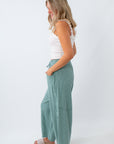 Woman wearing a white top and green pants on a white background