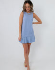 Side view of woman in blue sleeveless pleated hem mini dress with sunglasses and gold necklace
