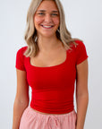 Woman wearing a red top and pink striped pants on a white background