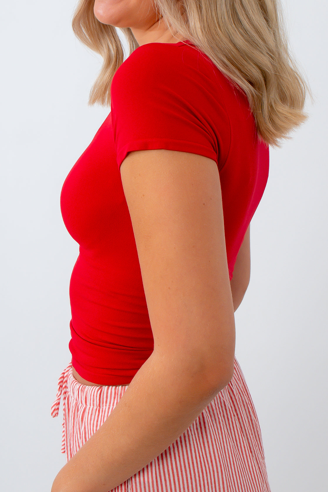 Person wearing a red top and striped skirt on a white background