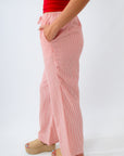 Person wearing pink striped pants and a red top on a white background