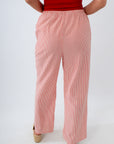 Person wearing a red top and pink striped pants on a white background