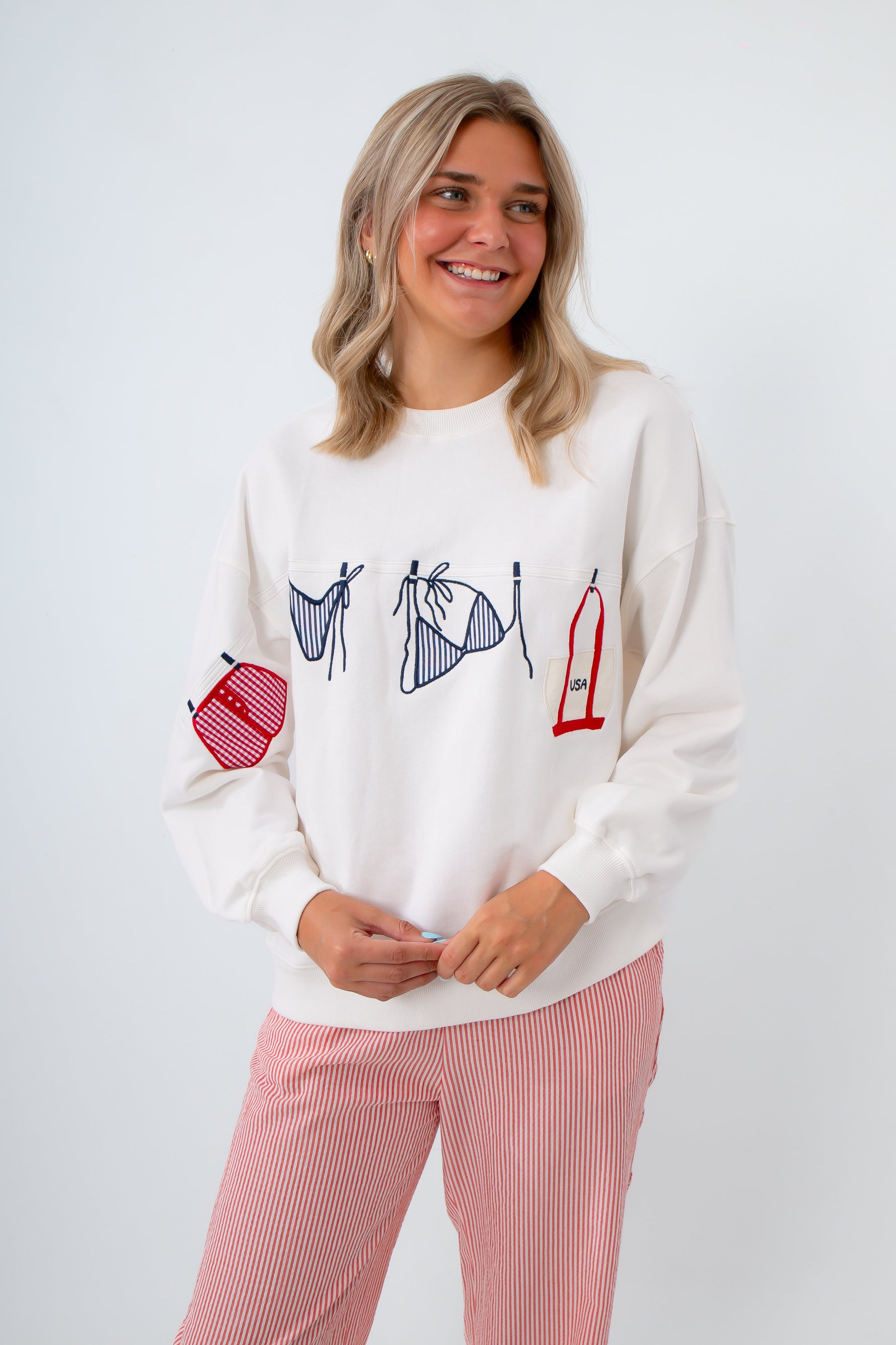 Woman wearing a white sweater with graphic designs on a white background
