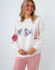 Woman wearing a white sweater with graphic designs on a white background