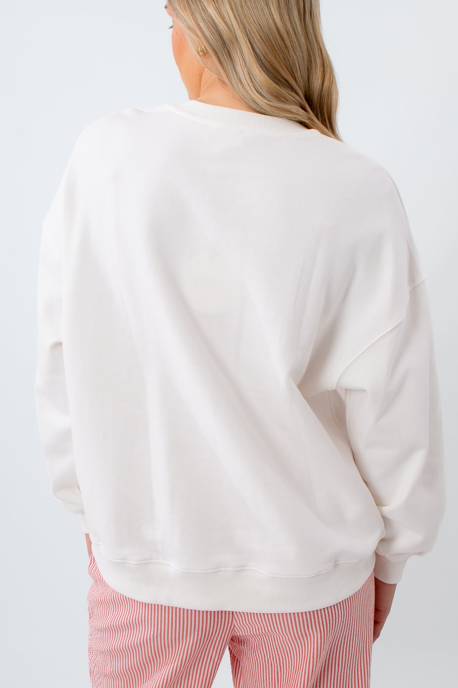 Person wearing a white sweatshirt and pink pants on a white background