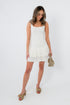 White mini dress with pleated hem, sleeveless, square neckline, stylish for parties and events