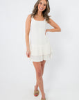 Model wearing white pleated mini dress with stylish bow heels, accessorized for a chic look