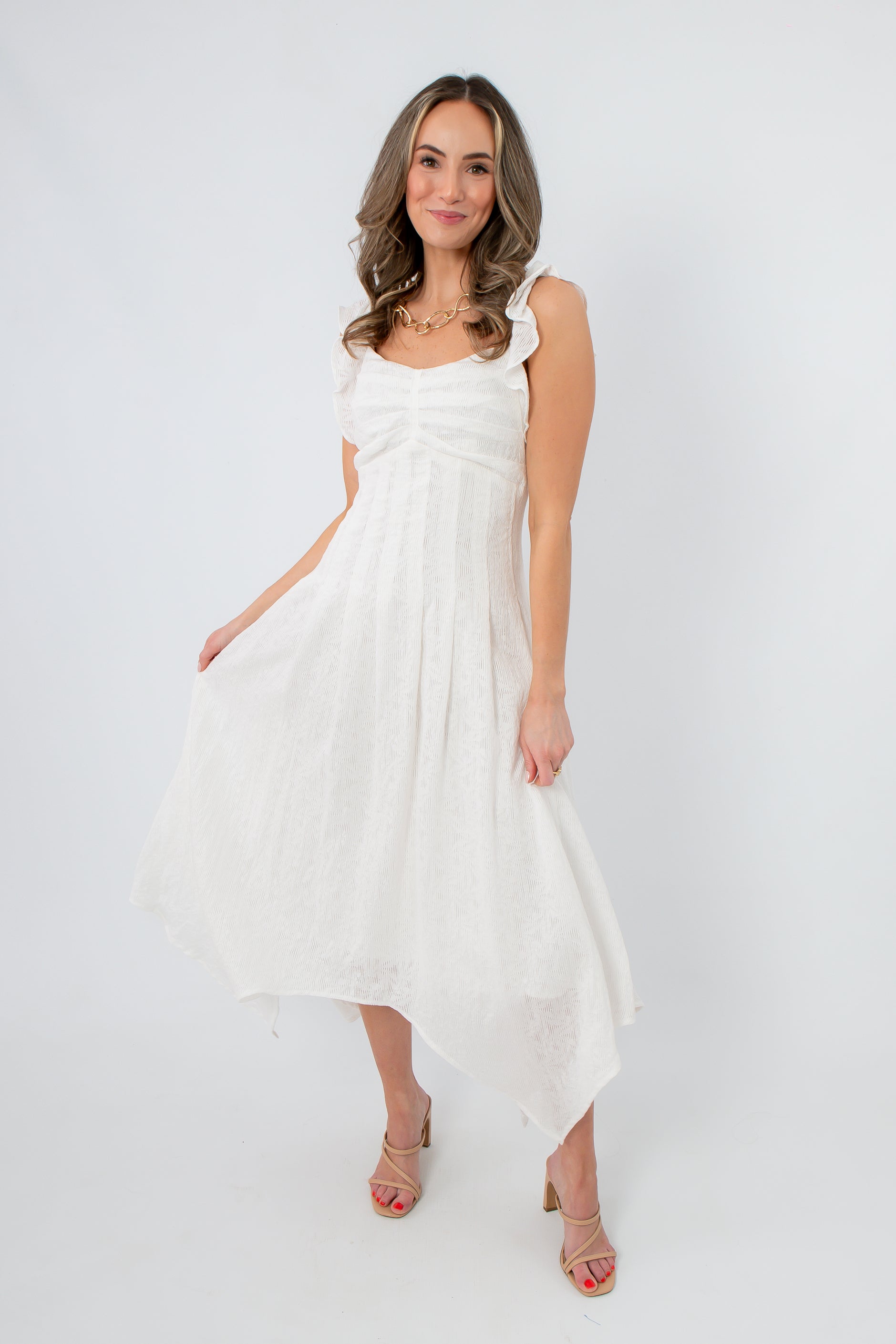 Elegant white midi dress with ruffled shoulder straps and asymmetrical hem, perfect for bridal showers
