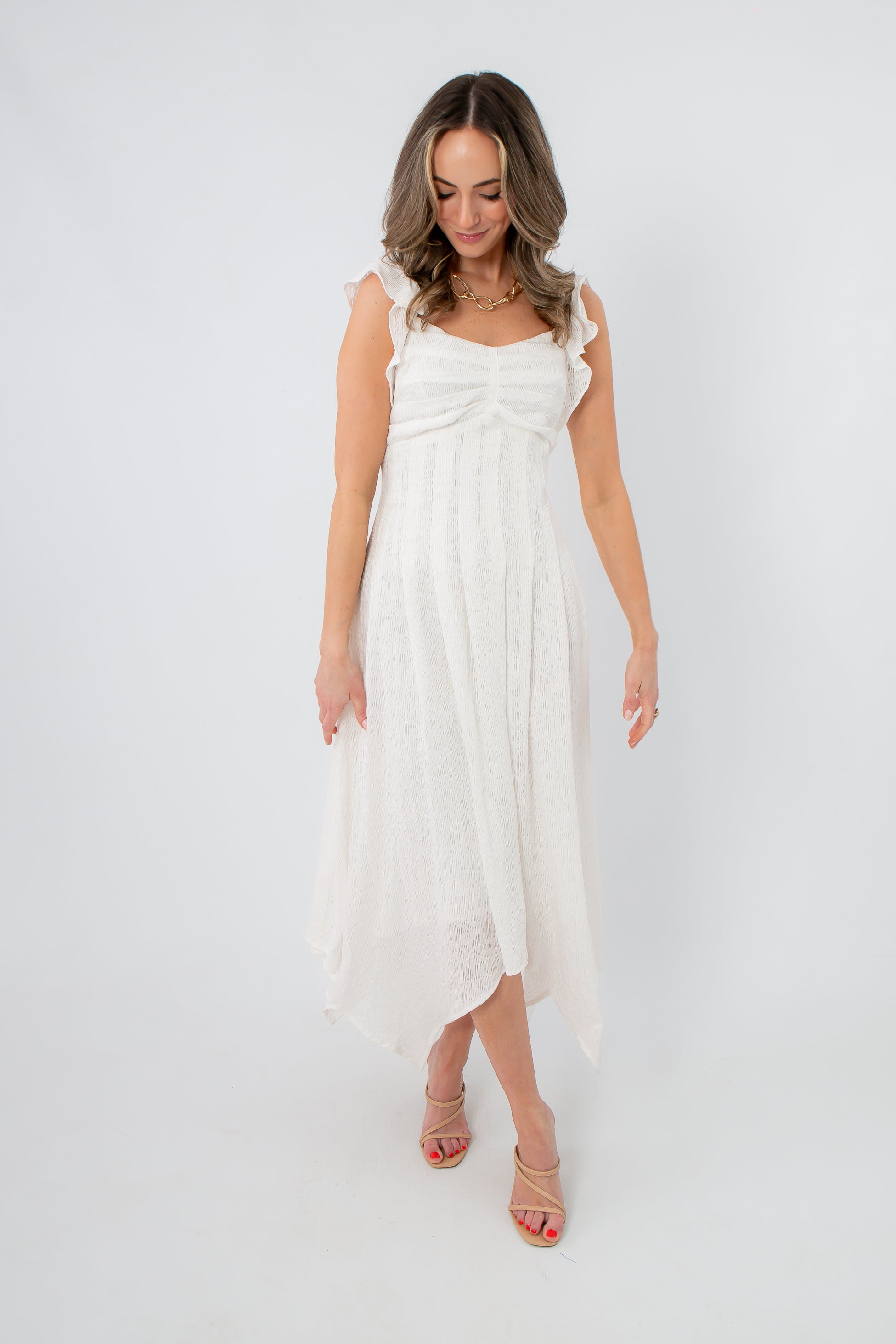 Back view of white sleeveless midi dress with ruffled shoulder straps and flowing asymmetrical hem