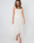Back view of white sleeveless midi dress with ruffled shoulder straps and flowing asymmetrical hem