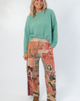 Model wearing Ori Howdy Drawstring Pants with turquoise sweater, showcasing western-themed pattern and comfortable fit.