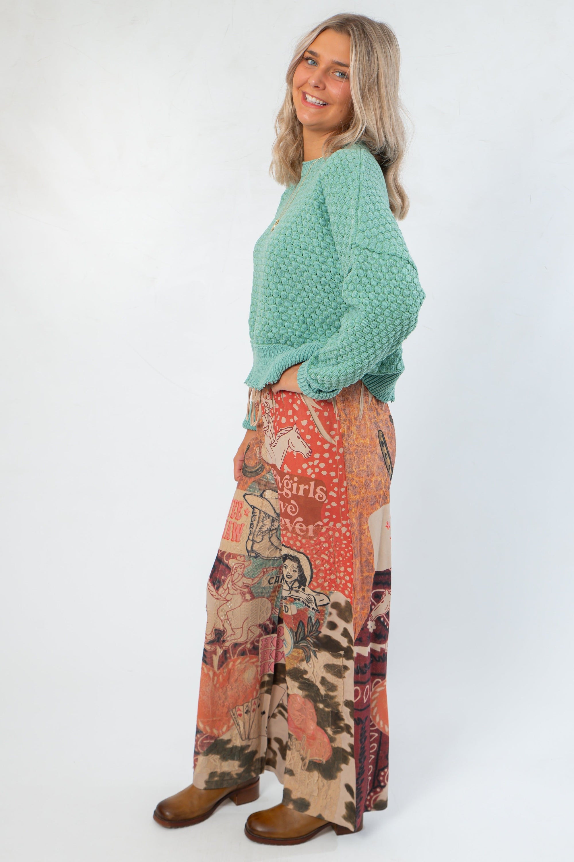 Side view of Ori Howdy Drawstring Pants with western illustrations and elastic drawstring waist, paired with casual knit top.