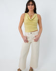 Model in yellow sleeveless cowl neck top with cream wide-leg pants and sandals