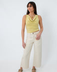 Close-up of model in yellow sleeveless cowl neck top with jewelry