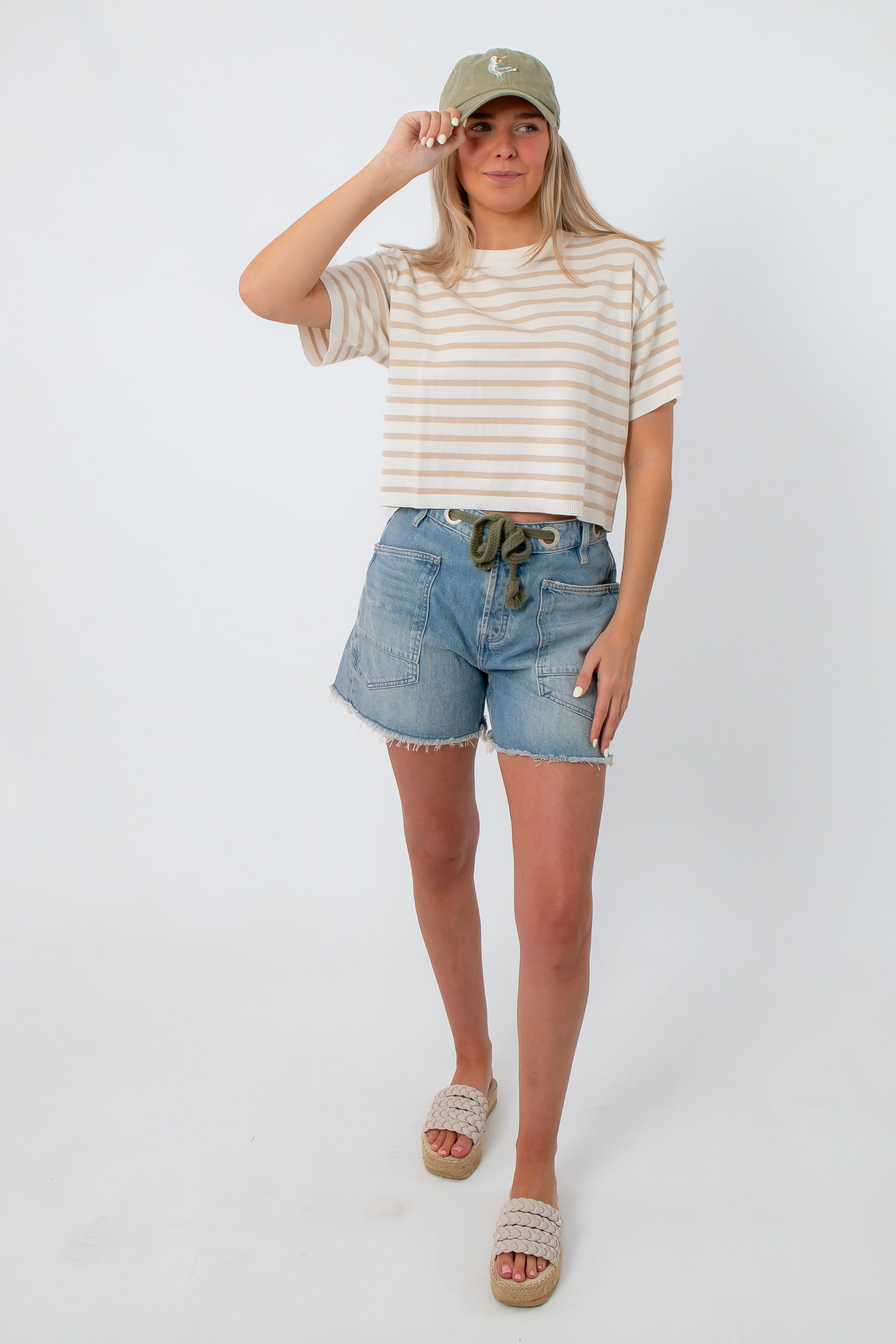 Casual striped knit tee with drop shoulders, beige and white, styled with denim shorts and a cap