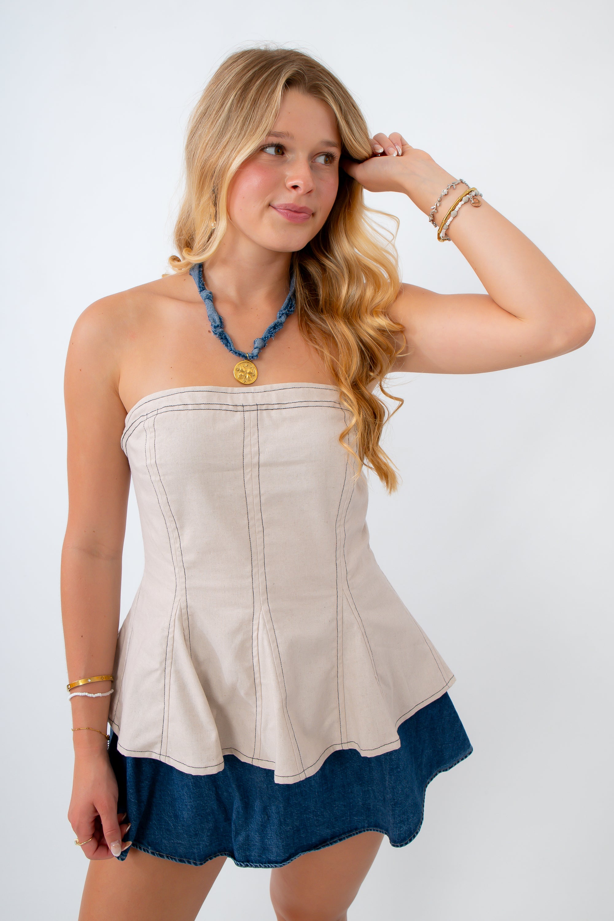Woman wearing a strapless top with a blue hem on a white background