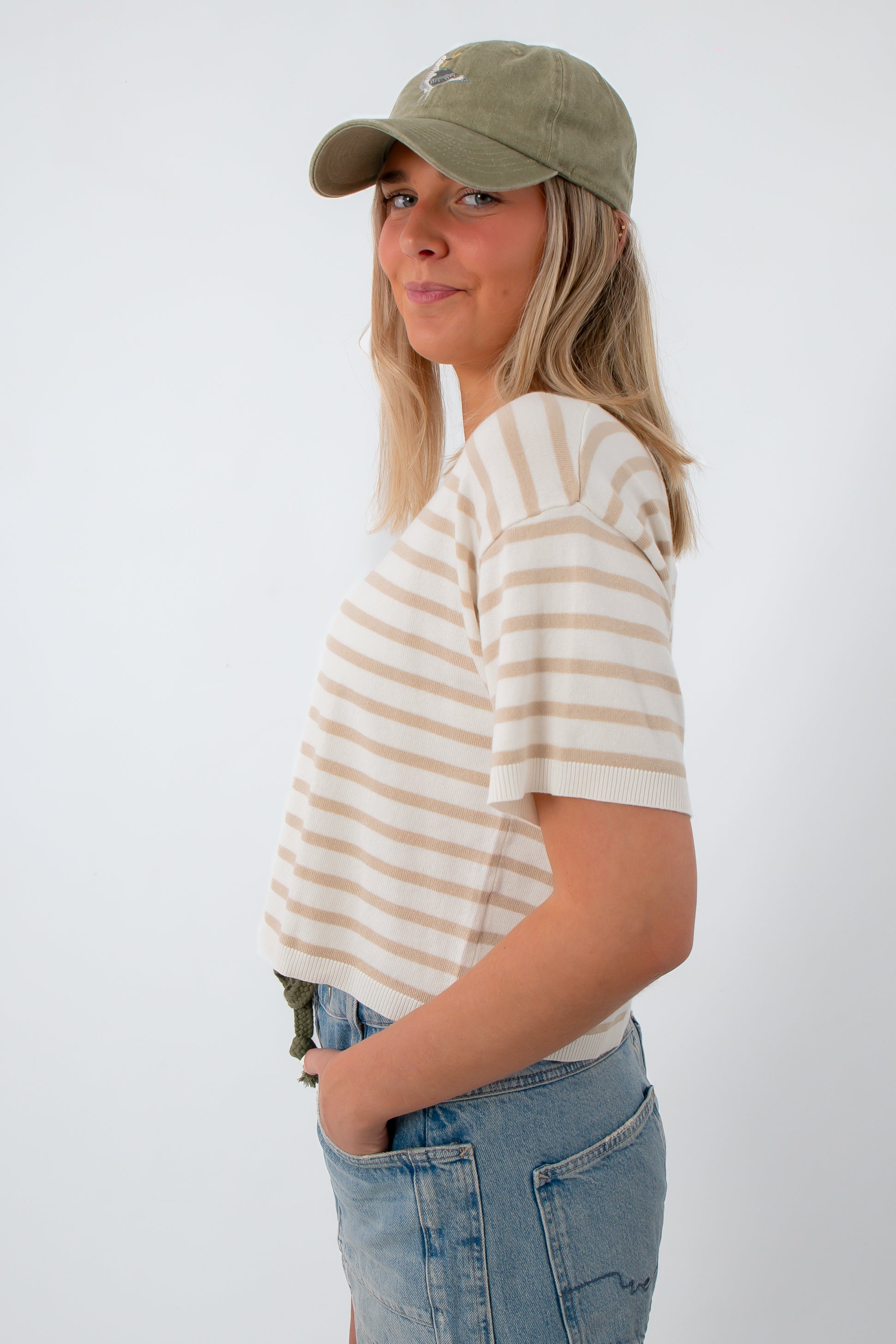 Women in striped knit tee, wearing baseball cap, casual look