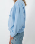Back view of light blue sweatshirt with 'Coast' graphic, casual women's apparel
