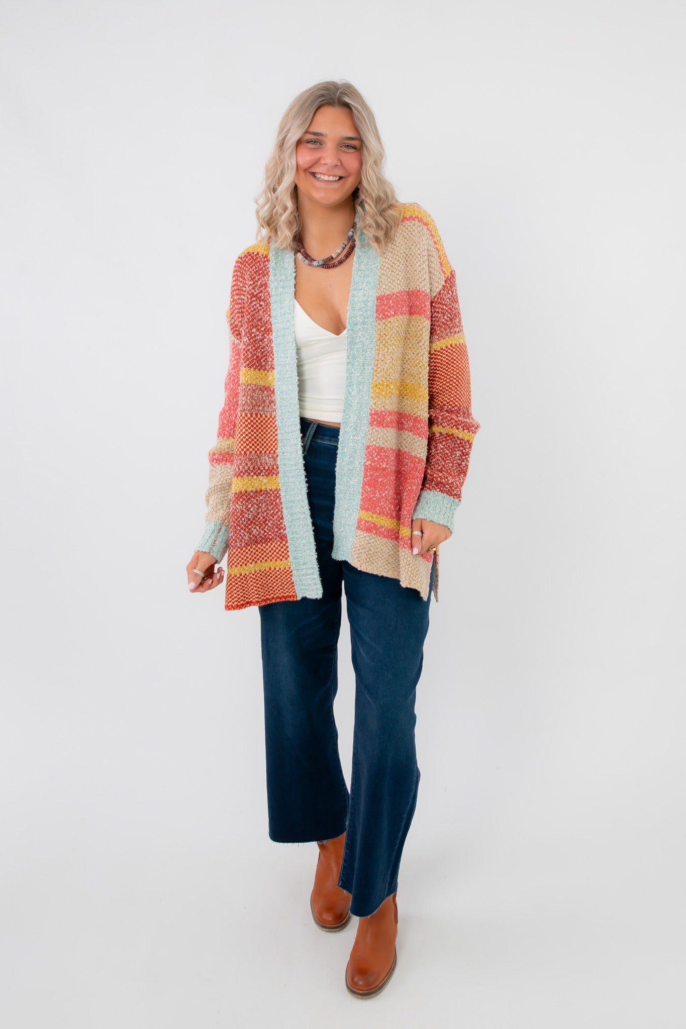 Iris Orange Stripe Open Cardigan – Oversized knit cardigan with multicolor stripes, drop shoulders, and front open design, styled with denim and boots.