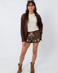 Women’s brown button-up shirt with long sleeves, paired with embroidered shorts and cowboy boots, front view