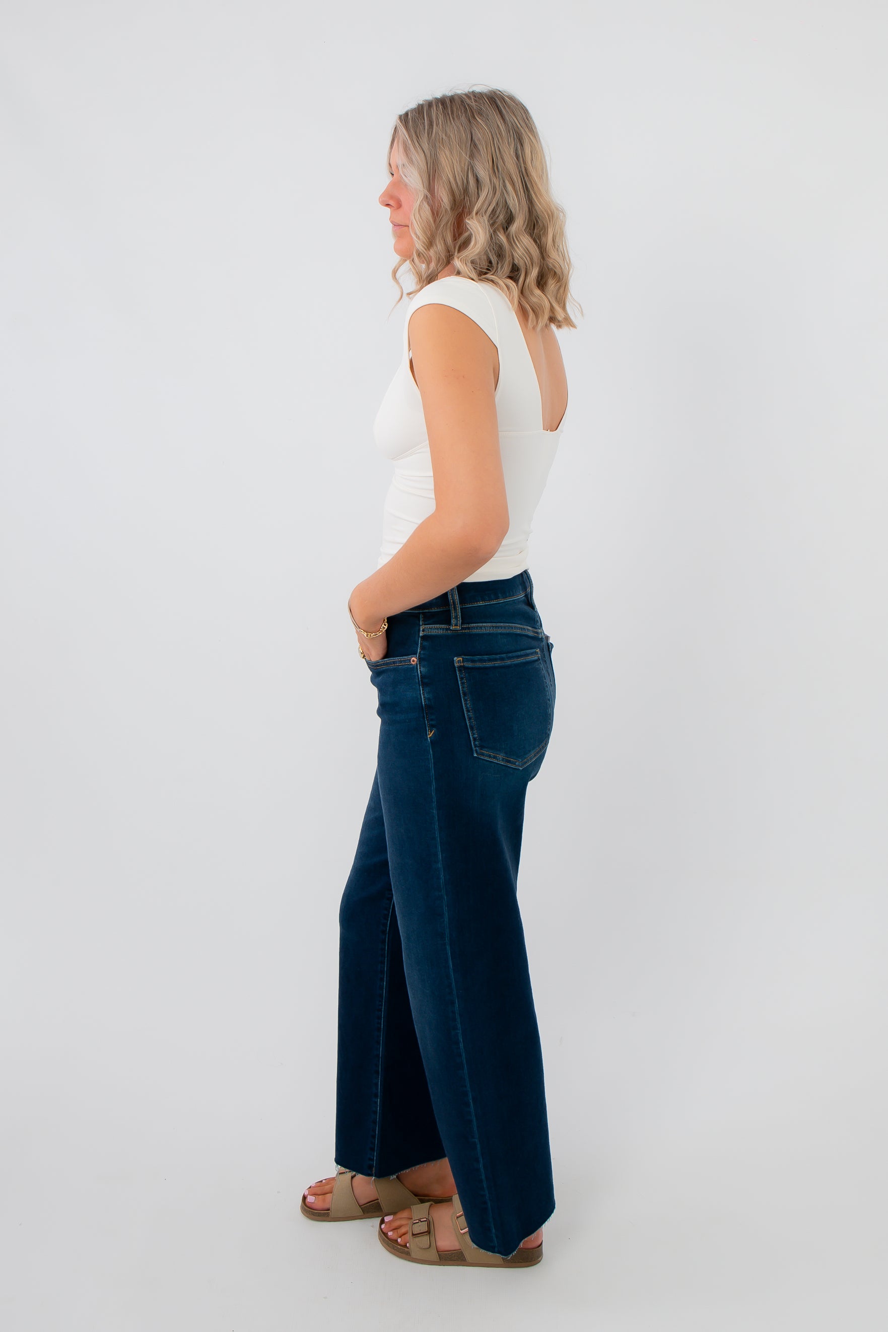 Side view of Free People Ivory Duo Corset Cami – Fitted ivory cami with cap sleeves and contoured shape, styled with dark wash wide-leg jeans.