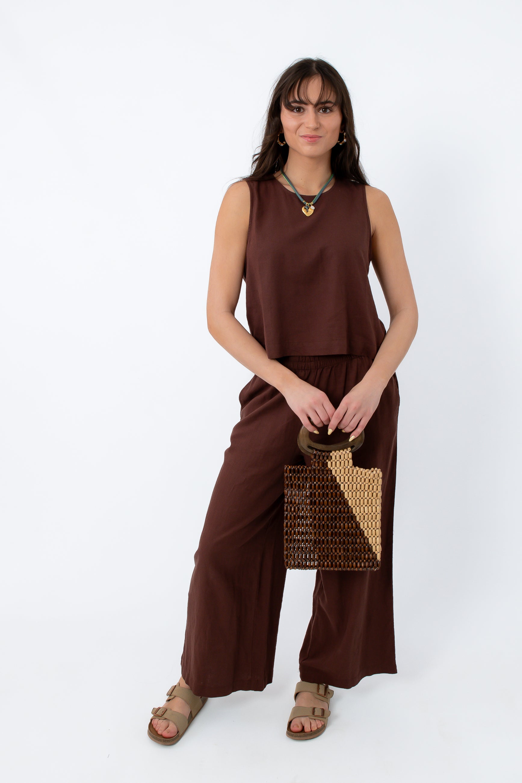 Back view of women in relaxed brown linen trousers with side pockets, styled with casual sandals