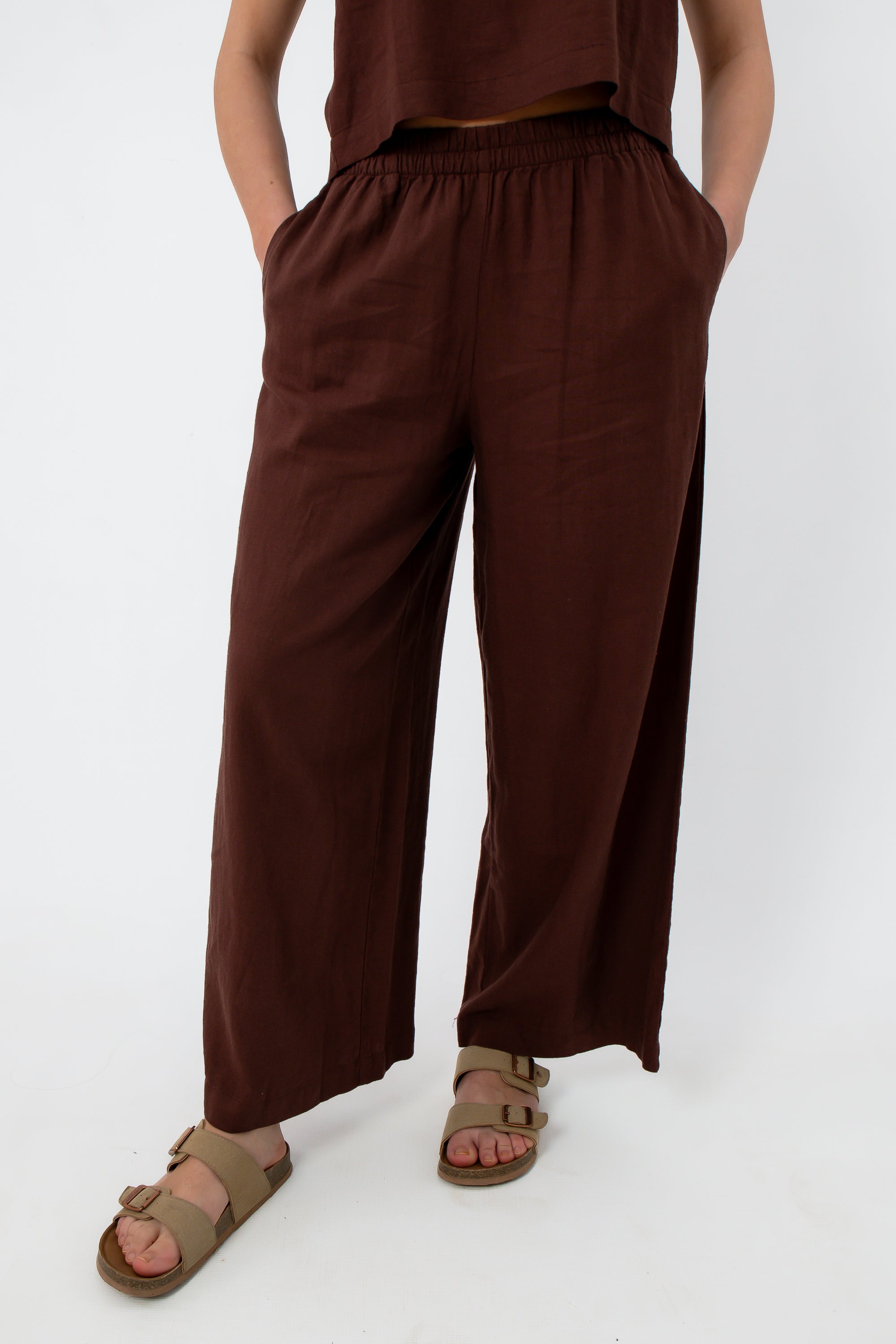 Close-up of women in brown linen pants with elastic waistband, showing relaxed fit and fabric texture