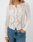 Close-up of white lace blouse with detailed embroidery and fitted style