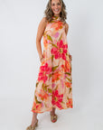 Side view of woman in floral maxi dress with large flower pattern, showing dress length and flowy style, wedding guest attire
