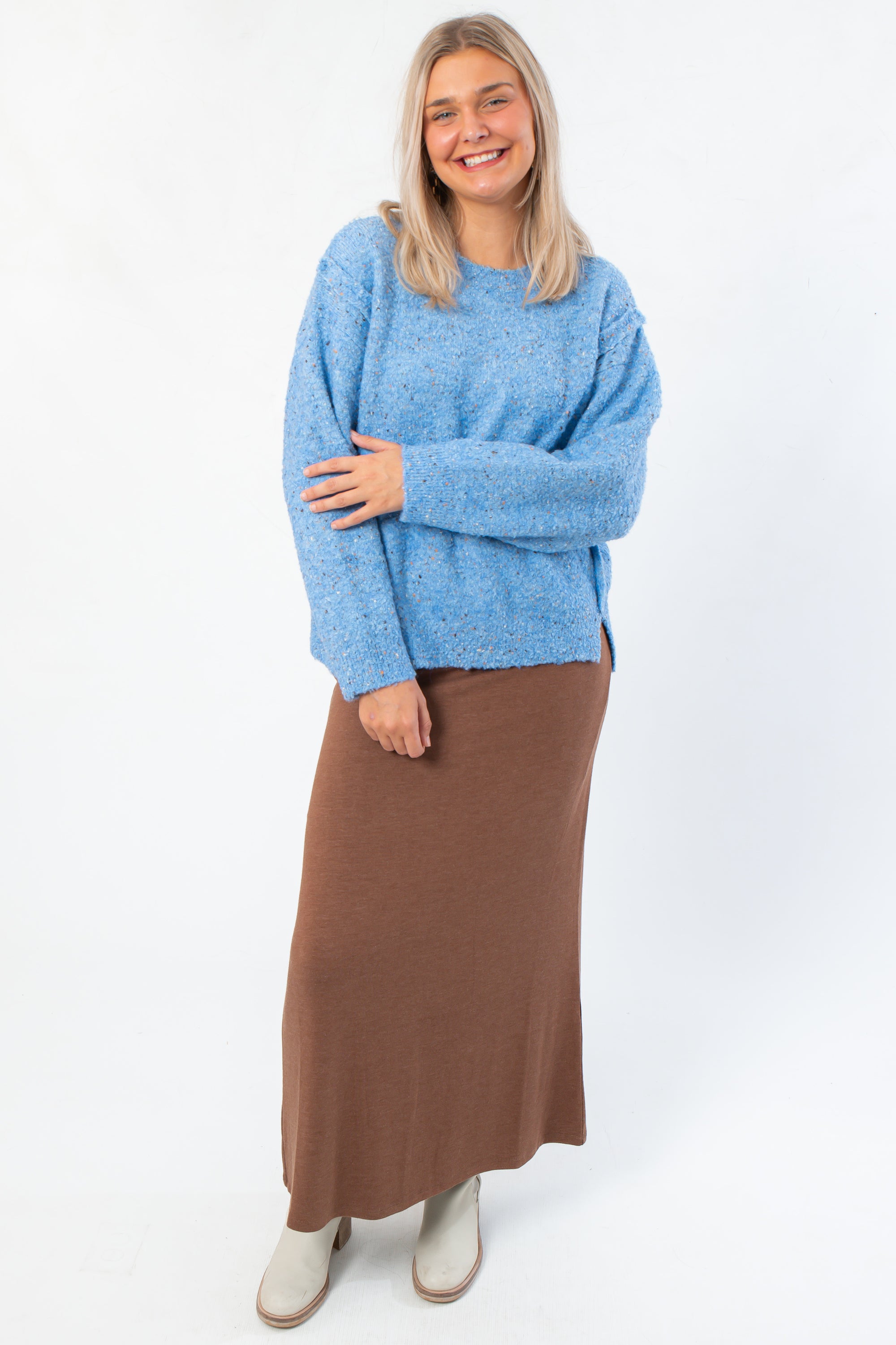 Cozy and stylish Lorelai Blue Marbled Round Neck Sweater featuring side slits and relaxed fit, paired with a long brown skirt and boots.