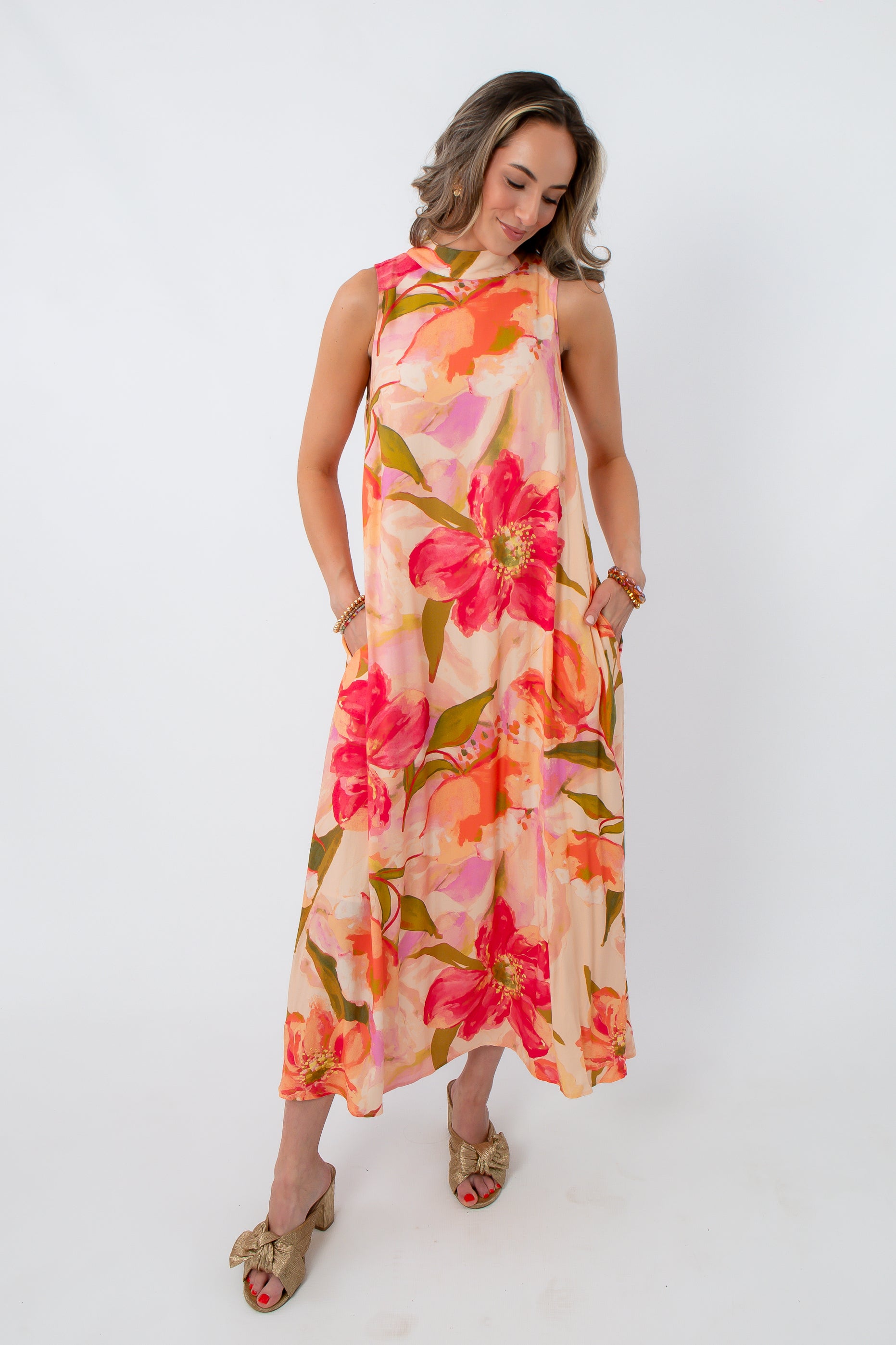 Vibrant floral maxi dress with large pink and orange flowers, sleeveless design, and pockets, perfect for wedding guests and summer occasions