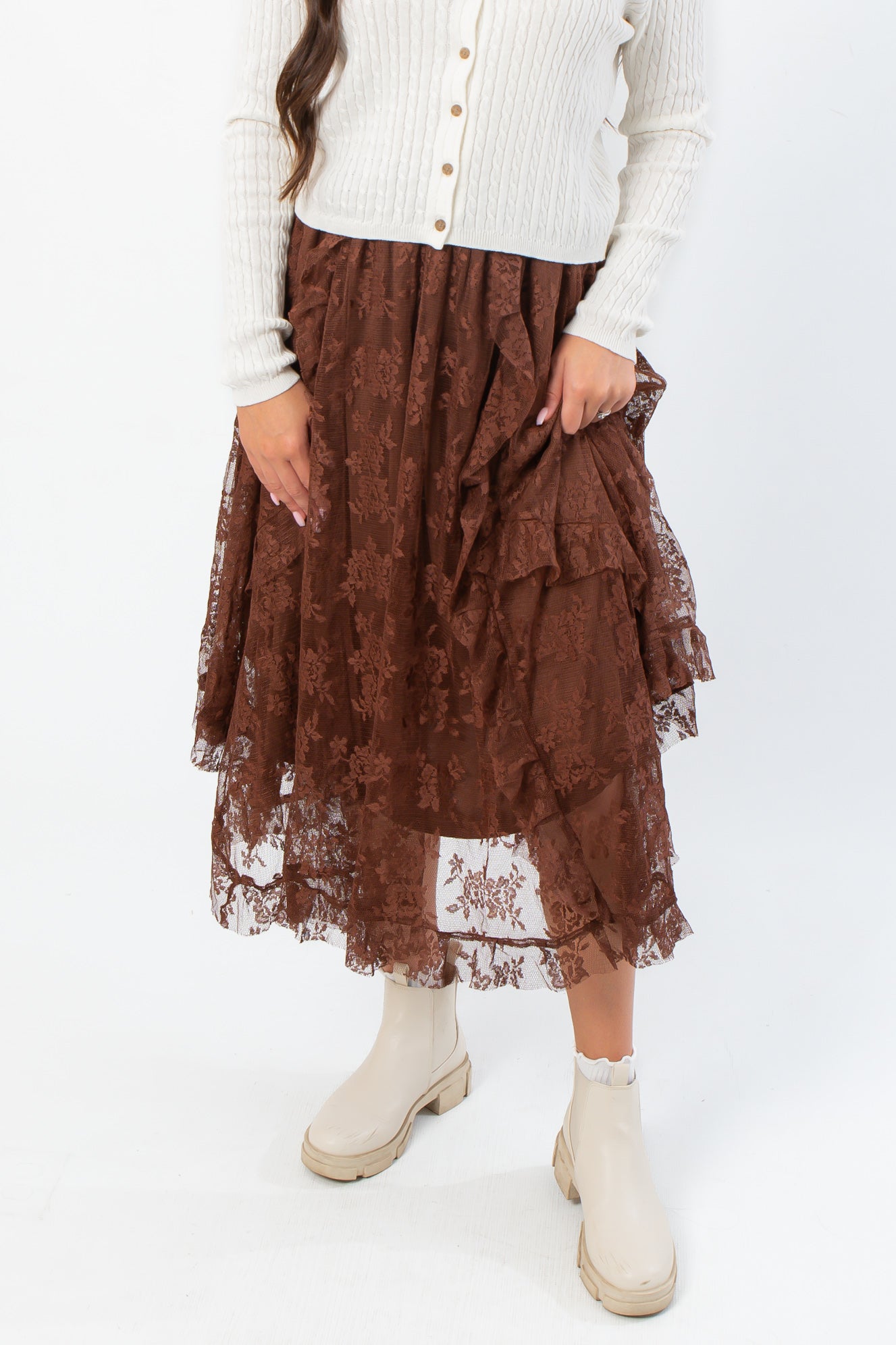 Serene Mocha Lace Maxi Skirt with ruffled layers and floral lace detail, styled with cream boots for a boho fall look.