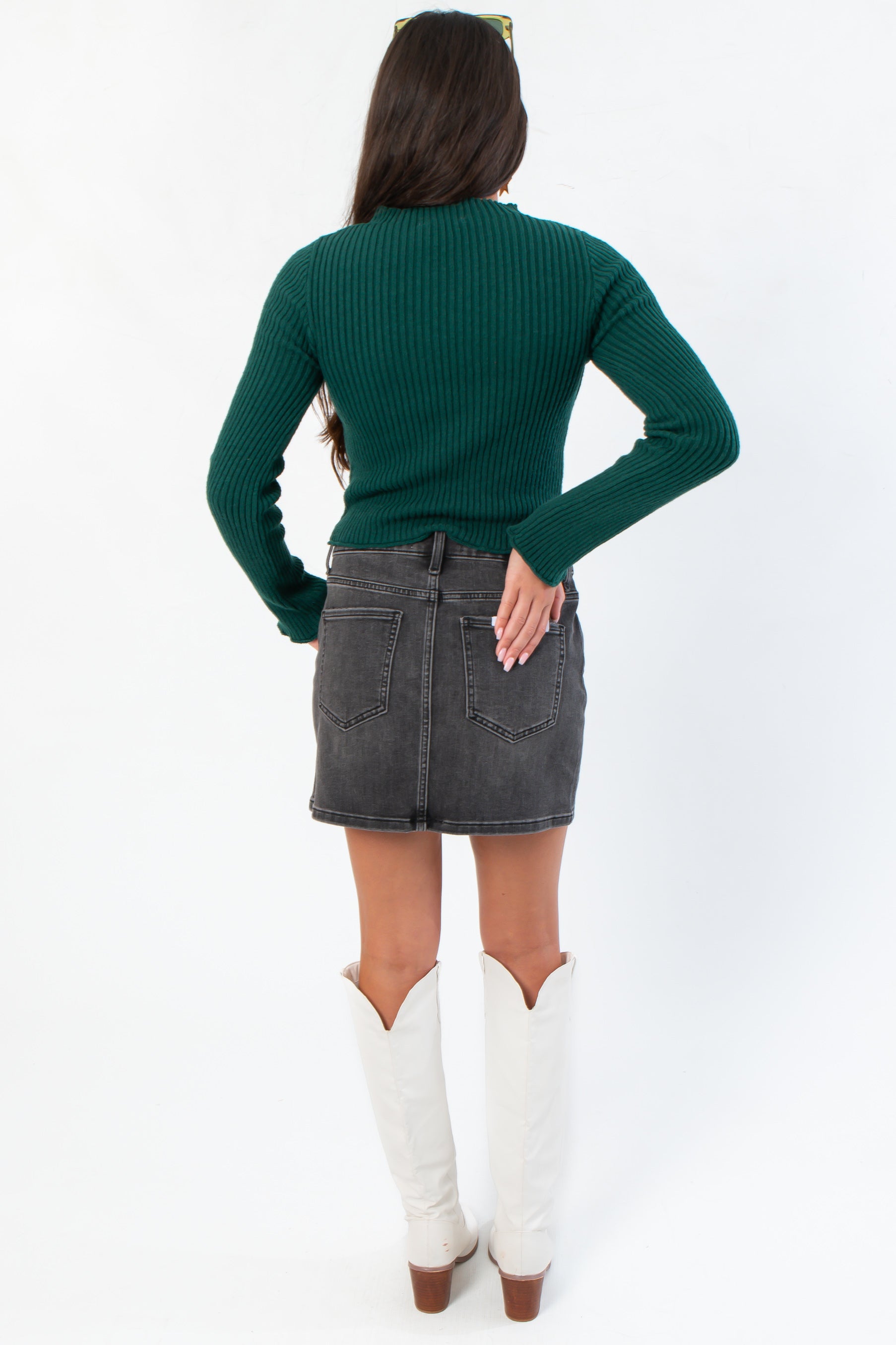 Back view of Taylor Emerald Green Ribbed Long Sleeve Top highlighting ribbed texture and snug fit, styled with a black denim skirt.