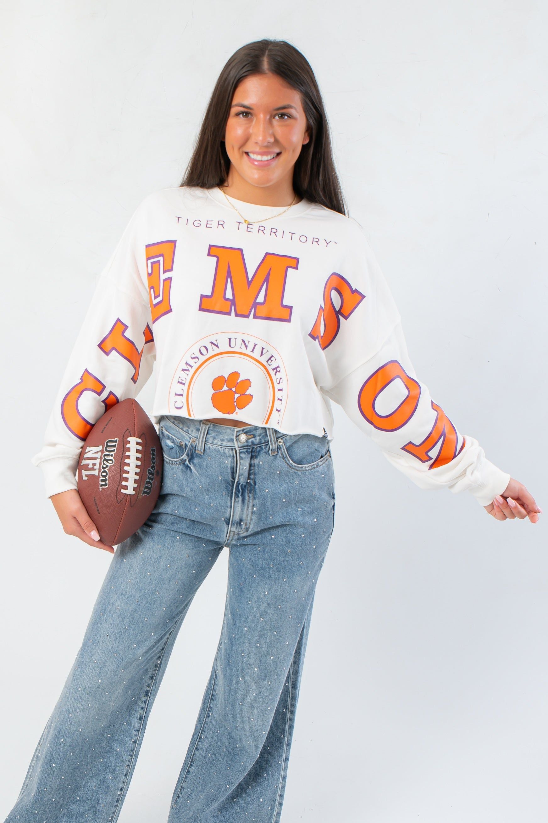 Clemson Phipps Cropped Long Sleeve Top with bold orange lettering and raw hem, styled for game day with a football prop.