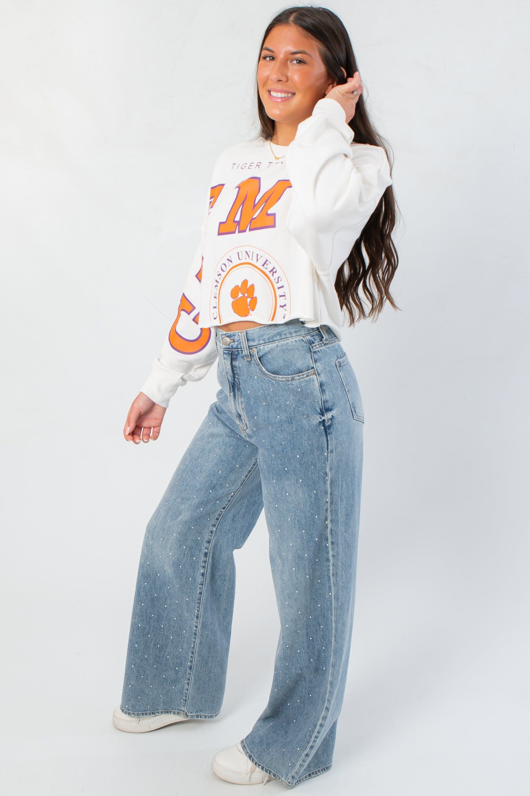 Side view of Clemson Phipps Cropped Long Sleeve Top showing relaxed fit and trendy cropped cut, paired with wide-leg jeans.