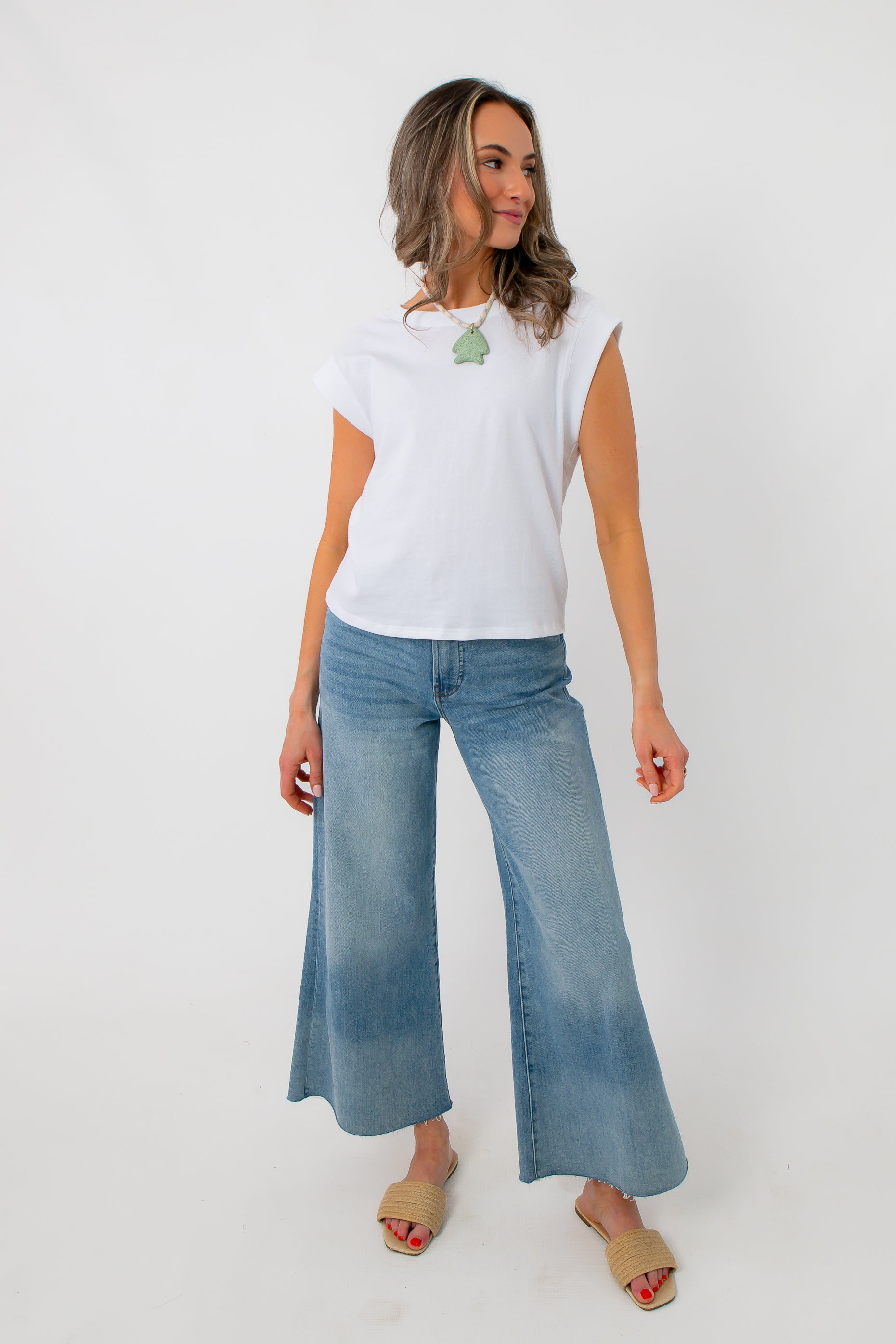 White sleeveless Jersey top styled with wide-leg jeans and beige slides