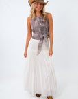 Woman wearing a sleeveless top and white skirt with a cowboy hat on a white background