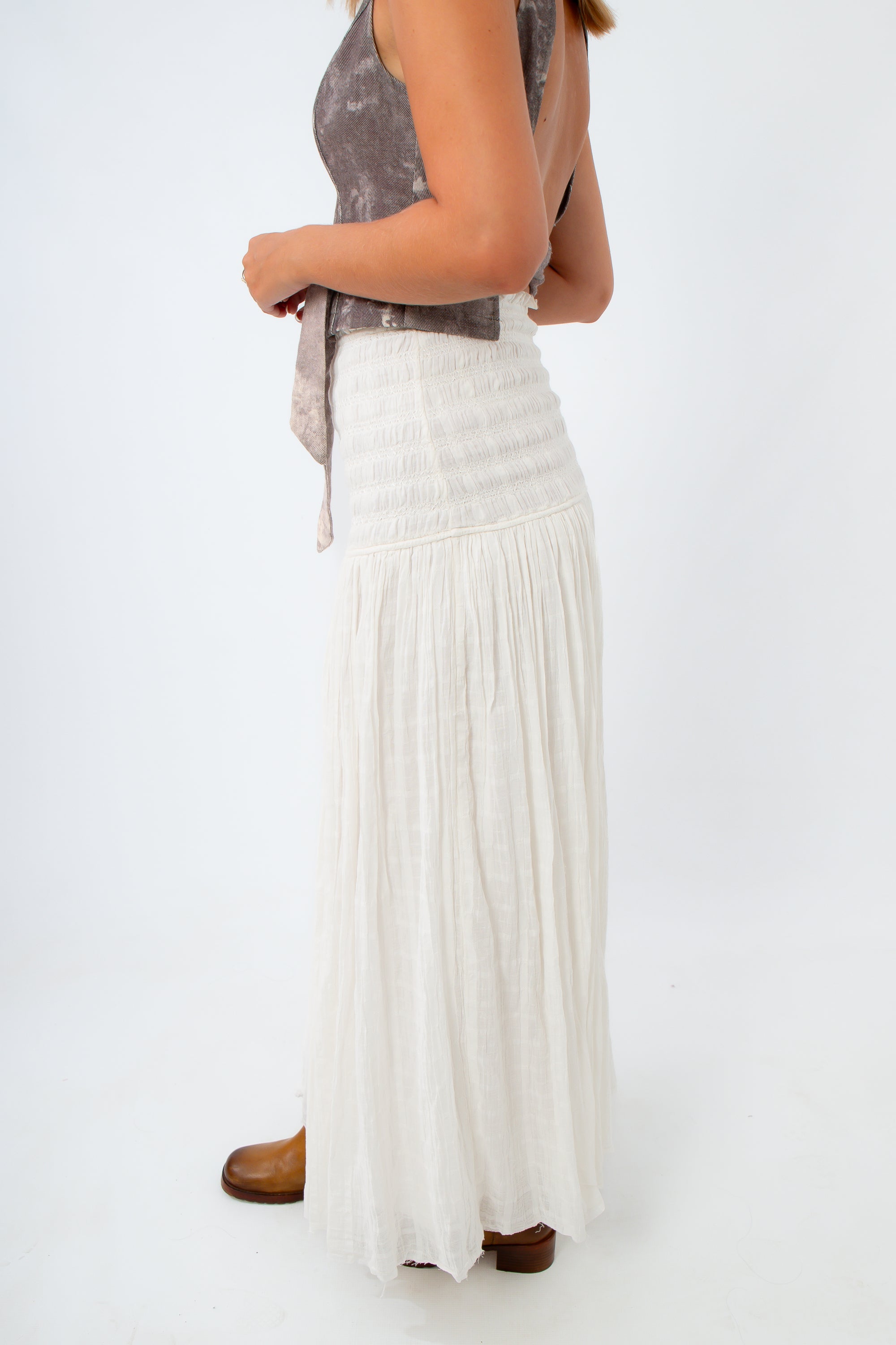 Person wearing a long white skirt on a plain background